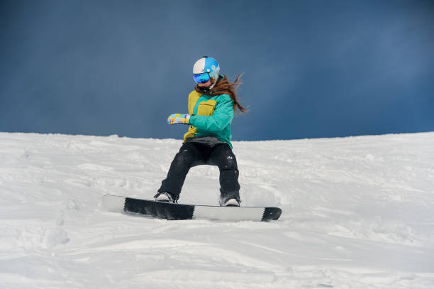 istock Female snowboarder riding down the mountain slope 1034270574