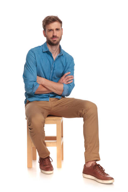 istock serious young casual man sitting with hands crossed 1034275210