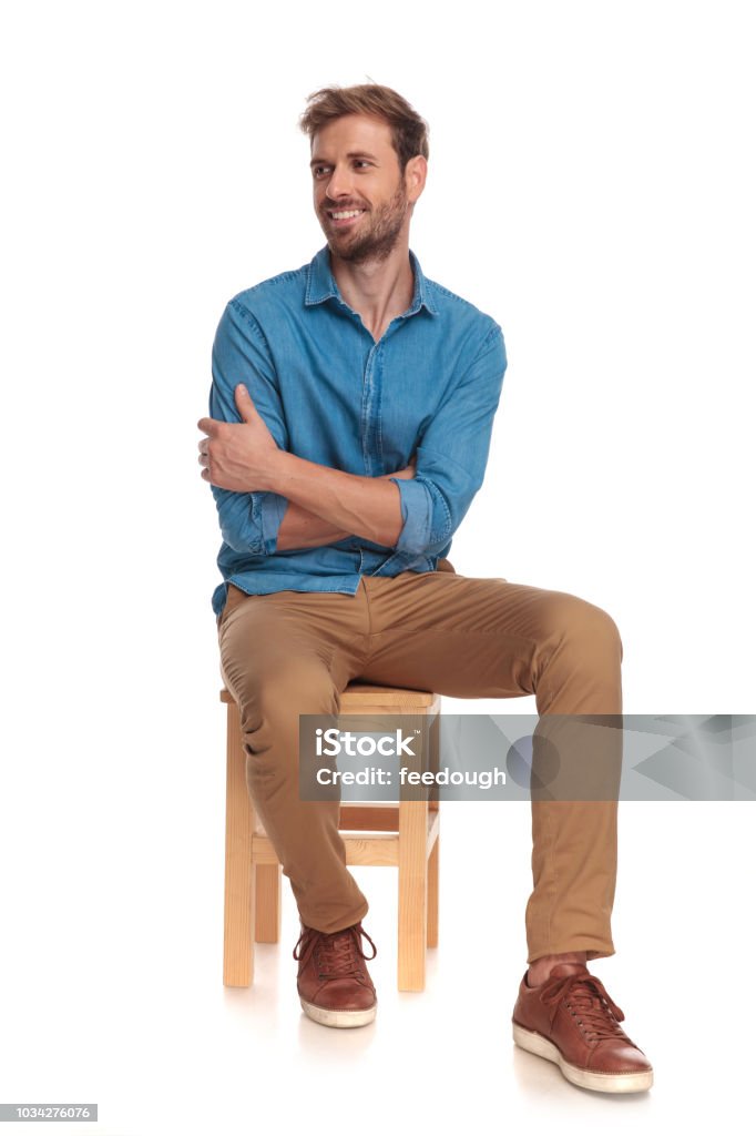 sonriendo sentado joven casual hombre mira hacia - Foto de stock de Sentado libre de derechos