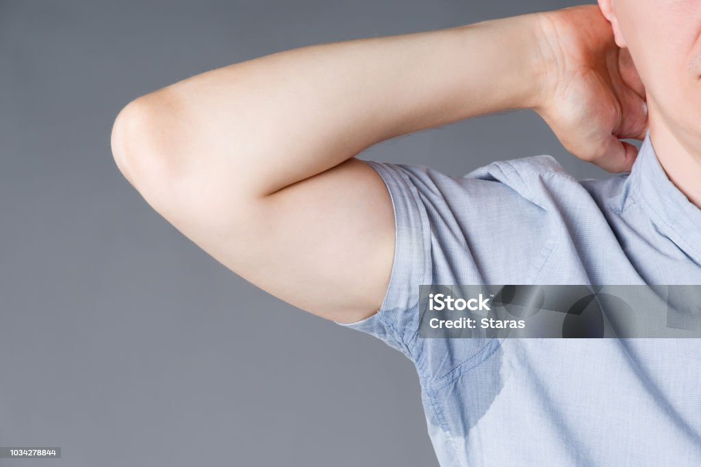 Mann mit verschwitzten Achselhöhlen auf grauem Hintergrund - Lizenzfrei Schweiß Stock-Foto