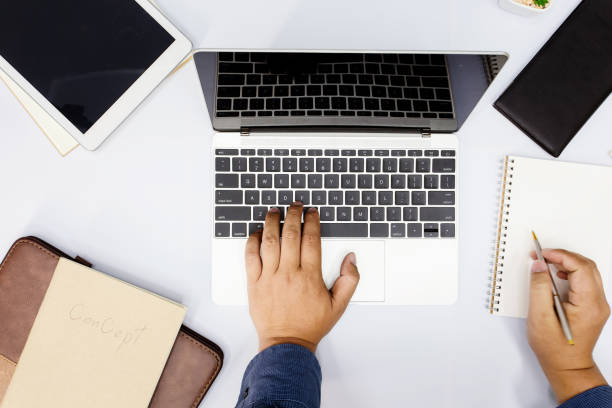 istock Businessman using computer laptop and other office supplies on white table in the office. Top view 1034279114
