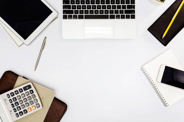 istock White office desk. table with blank notebook, tablet, calculator, computer and other office supplies. Top view with copy space. 1034279296