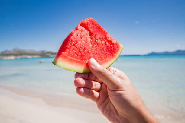 Hand holding slice of ripe red watermelon stock photo