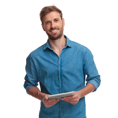 smiling young casual man holding a tablet pad computer on white background