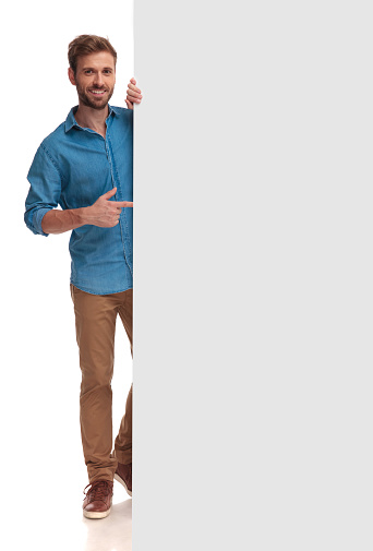 happy casual man pointing finger at a blank board on white background