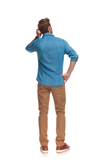 back view of a young casual man scratching his head back view of a young casual man scratching his head on white background worried man standing stock pictures, royalty-free photos & images