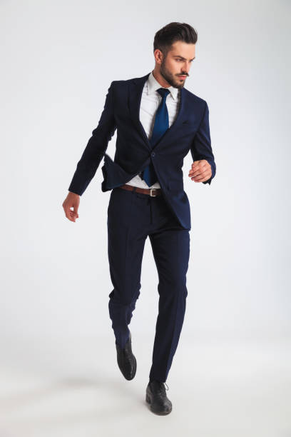 istock confident businessman in navy suit walking while looking to side 1034288132