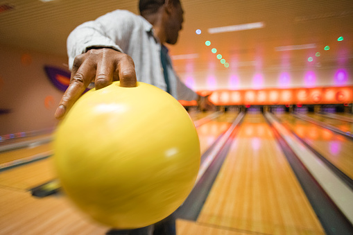 Rear, close-up shot of a senior man about to throw a bowling ball down the bowling alley.