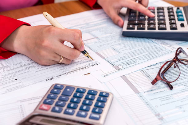 istock Female hand filling 1040 form and calculating 1034297930