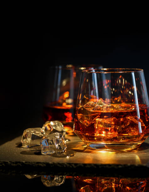 istock Two glasses of whiskey with ice on a black background 1034299110