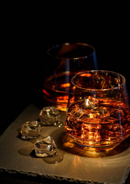 istock Two glasses of whiskey with ice on a black background 1034299146