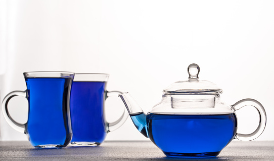 Cup and teapot of butterfly pea tea isolated on white background.