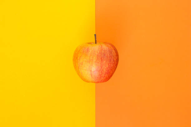 istock red apple on orange and yellow background 1034302944