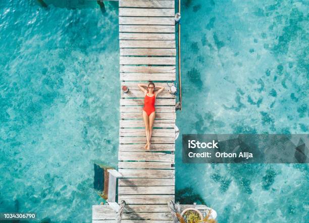 Aerial Shot Of Womann Relaxing In A Water Bungalow Stock Photo - Download Image Now - Beach, Vacations, Women