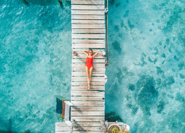 aerial shot de womann relaxante em um bangalô de água - standing water - fotografias e filmes do acervo