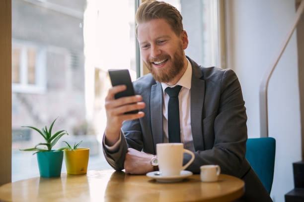 istock Smiling businessman texting in a cafe 1034313516