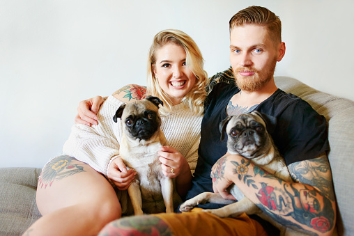 Shot of an affectionate young couple playing with their dogs at home