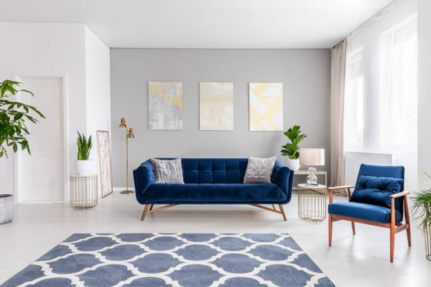 interior del salón de espacio abierto con un sofá azul marino y un sillón. alfombra en el piso y decoraciones del gráfico en la pared. foto real. - cushion pillow textile luxury fotografías e imágenes de stock