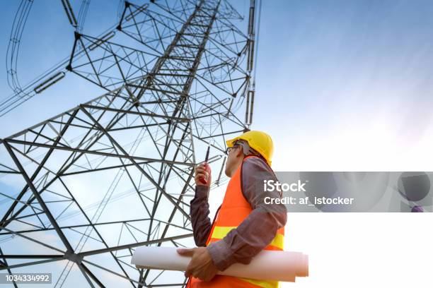 Construction Worker Checking Location Site Near To High Voltage Tower Stock Photo - Download Image Now