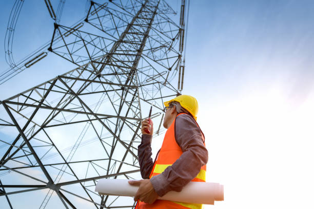 construction worker checking location site near to high voltage tower. - torre de transmissão de eletricidade imagens e fotografias de stock
