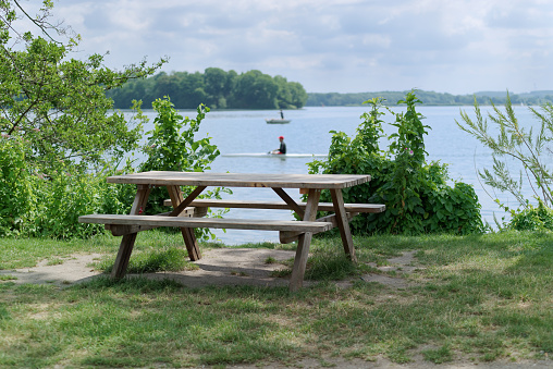 Picnic place at the lake coast - tranquil scene of wooden table with two benches at the lake coast. Malente, Germany