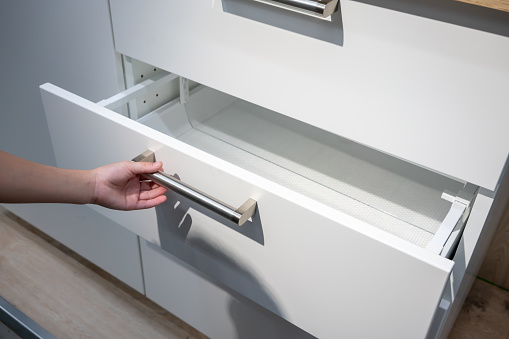 Woman hand pulling a drawer organized with additional plastic inside.