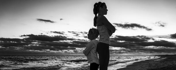 istock mother and child on beach on sunset standing back to back 1034352644
