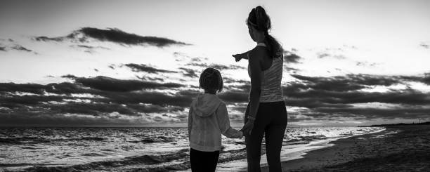 istock mother and child on seashore on sunset pointing at something 1034352678