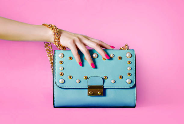 sky blue handbag purse and beautiful woman hand with red manicure isolated on pink background. - purse bag glamour personal accessory imagens e fotografias de stock