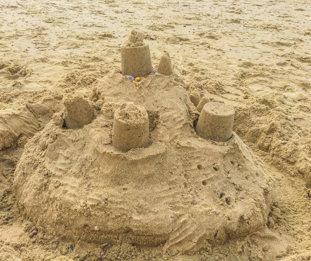 istock Sand castle construction with towers and shells on the beach sand landscape 1034357540