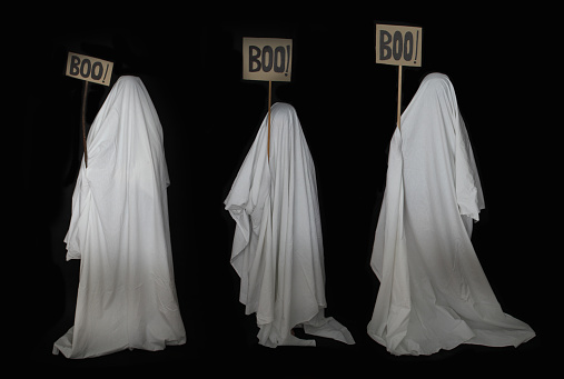 three people disguised as ghosts with a white sheet