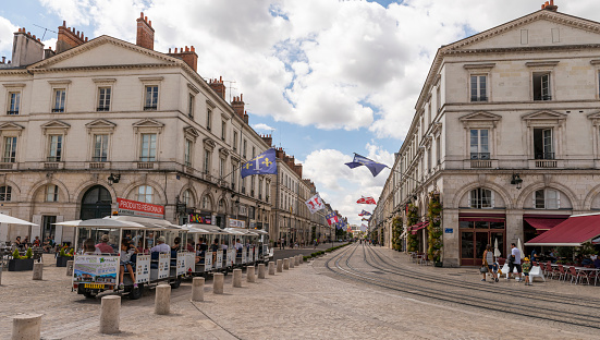 Orleans, France - August 11, 2018: City of Orleans with public transport (touristic train), street with flags and banners and tourists, Loiret, France.