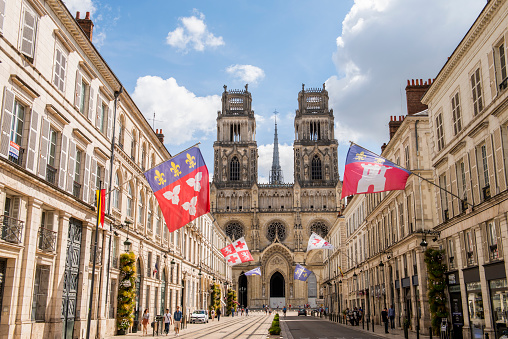 Orleans, France - August 11, 2018: City of Orleans with cathedral, street with flags and banners and shopping tourists, Loiret, France.