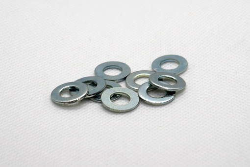Close up view of a group of steel flat washers. Taken inside a softbox with white floor