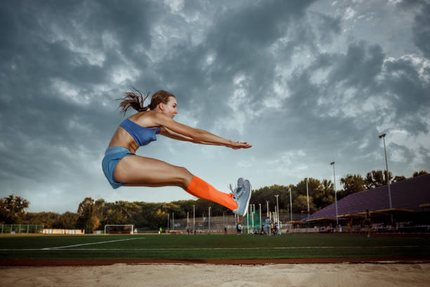 mujer atleta realizando un salto de longitud durante una competición - track and field athlete women vitality speed fotografías e imágenes de stock