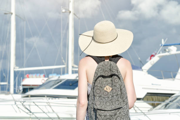 istock Girl in a hat with a backpack near ship. Back view 1034373446
