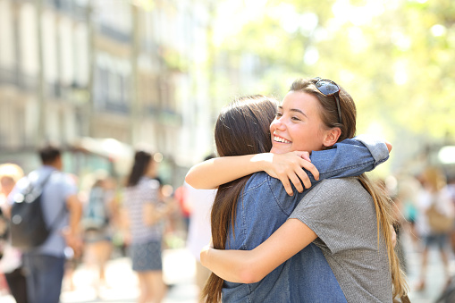 Friends meeting and hugging in the street