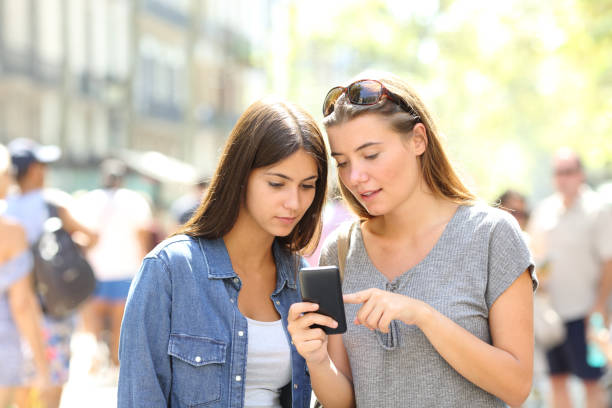 istock Girls talking about online content in a smart phone 1034373710