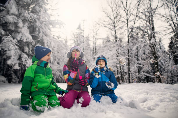 istock Happy kids blowing bubbles in winter forest 1034375852