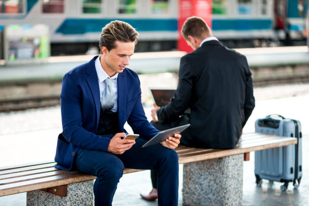 istock Two businessmen on a train station using laptop and digital tablet 1034378956