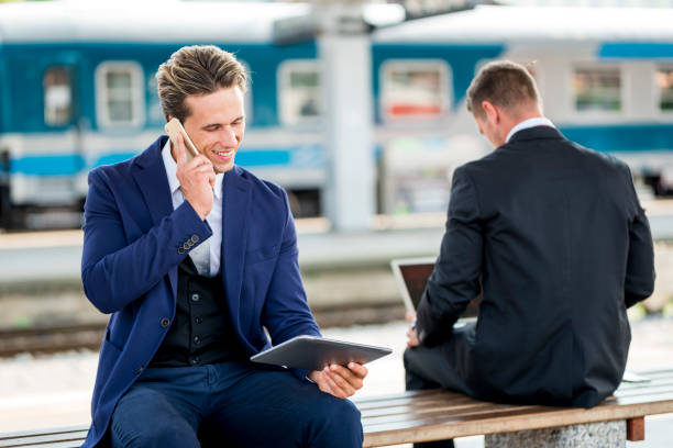 istock Two businessmen on a train station using laptop and digital tablet 1034378988