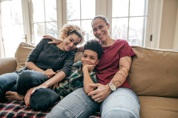 Health insurance for the family Lesbian couple and a boy sitting and smiling. homosexual stock pictures, royalty-free photos & images