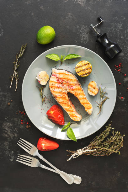 istock Grilled salmon steak served on a gray plate, black concrete background. Top view,flat lay. 1034388026