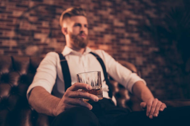 istock Handsome wealthy confident serious relaxed stunning wealthy successful professional brutal chic elegant posh classy model sitting in chair enjoying whiskey in hand glass is in focus 1034390826