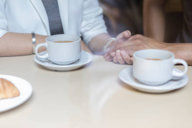 istock Unrecognizable couple hold hands in coffee shop 1034399432