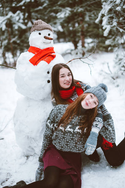 Two young teenage hipster girl friends together.Close up fashion portrait of two sisters hugs and having fun winter time,wearing sweater,best friends couple outdoors, snowy weather dos jóvenes adolescentes hipster amigas juntos. retrato de moda de dos hermanas abrazos de cerca y divertirse, hacer muñeco de nieve en el bosque del tiempo de invierno, usa suéteres y bufandas, mejor pareja de amigos al aire libre, tiempo nevoso