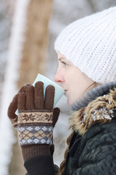 istock Girl in winter clothes drinking tea from a mug. Side view. close-up 1034408522