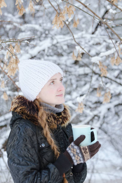 istock Girl in a white hat with cup of tea. Winter, outdoors. Side view 1034408528