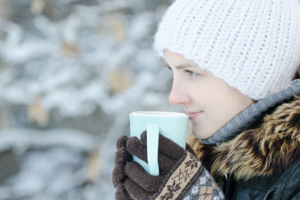 istock Girl in winter clothes drinking tea from a mug. Side view. close-up 1034408532
