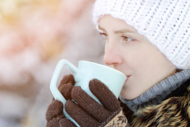istock Girl in winter clothes drinking tea from a mug. Side view. close-up 1034408538